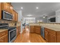 View of kitchen with stainless steel appliances, granite countertops, and wood floors at 3003 Weston Green Loop, Cary, NC 27513