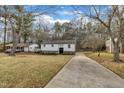 Charming white home with a neatly manicured lawn, complemented by lush greenery and a long driveway at 305 November St, Garner, NC 27529