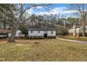 Charming white home with a neatly manicured lawn, complemented by lush greenery and a long driveway at 305 November St, Garner, NC 27529