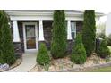Inviting front porch with stone accents, green landscaping, and clear view of front door with address number 401 at 401 Lawton Dr, Haw River, NC 27258