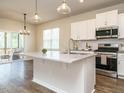 Bright kitchen featuring a center island with sink, granite countertops, stainless steel appliances and white cabinets at 50 Dover Ridge Ct, Chapel Hill, NC 27517