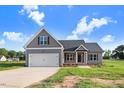 Charming single-Gathering home with grey siding, white trim, and an attached garage with concrete driveway and lawn at 9315 Turkey Way, Middlesex, NC 27557