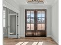 Inviting foyer featuring hardwood floors, a decorative ceiling, and a dark wood double front door at 100 Sire Ct, Holly Springs, NC 27540