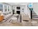Bright living room featuring a fireplace, large windows, modern furniture and an adjacent staircase at 120 Breyla Way, Holly Springs, NC 27540