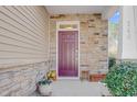 Inviting front entryway with a colorful door, stone accents, and decorative potted plants at 146 Skyros Loop, Cary, NC 27519