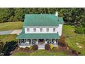 Aerial front view of home with a green metal roof, inviting porch, and manicured landscaping at 220 Epps Clark Rd, Siler City, NC 27344