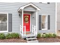 Close-up of a bright red front door with white trim and decorative wreath, complemented by gray siding at 3212 Oxford Dr, Durham, NC 27707