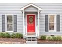 View of the home's red front door with a decorative wreath and gray siding with black shutters at 3212 Oxford Dr, Durham, NC 27707