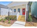 Close up of the home's front porch featuring a vibrant red door and wood stairs at 122 Weavers Grove Dr, Chapel Hill, NC 27514