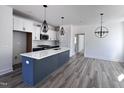 Modern kitchen featuring stainless steel appliances, white cabinets, a gray island with pendant lights and hardwood floors at 138 Weavers Grove Dr, Chapel Hill, NC 27514