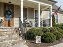 Cozy front porch with rocking chairs, stone steps, and a beautifully decorated wood door at 2609 at 2609 Packhouse Rd, Zebulon, NC 27597