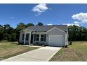 Single-Gathering home featuring gray siding, a black roof, a well-manicured lawn, and a driveway leading to an attached garage at 272 Johnson Ridge Way, Four Oaks, NC 27524