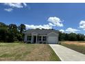 Single-Gathering home featuring gray siding, a black roof, a well-manicured lawn, and a driveway leading to an attached garage at 272 Johnson Ridge Way, Four Oaks, NC 27524
