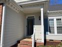 Close-up of a home's entryway, featuring a well-lit porch with brick steps and a storm door at 100 Sandy Hook Way, Cary, NC 27513