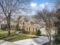 Beautiful brick home with a long driveway and attached garage, surrounded by lush greenery and trees at 102 Shepton Dr, Cary, NC 27519