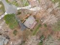 Aerial view of a property with a large deck, driveway, and mature trees surrounding the home at 115 Perth Pl, Durham, NC 27712