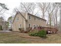 Tan home with a wooden deck and neutral trim surrounded by mature trees and minimal landscaping at 115 Perth Pl, Durham, NC 27712