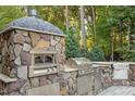 A well-equipped outdoor kitchen, complete with a pizza oven, grill, stainless steel cabinets, and stone accents at 1608 Doubles Ct, Raleigh, NC 27609