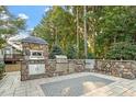 An elaborate outdoor kitchen featuring stone finishes, stainless steel appliances, and a patterned stone patio at 1608 Doubles Ct, Raleigh, NC 27609
