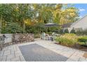 Inviting outdoor patio featuring a stone kitchen, comfortable seating, lush landscaping, and stone pavers at 1608 Doubles Ct, Raleigh, NC 27609