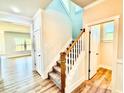 A view of the carpeted stairs with wood handrail leading to the second story, adjacent to the doorway and wood flooring at 22 Whistling Way # Holly Farmhouse, Lillington, NC 27546