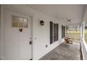 Inviting front porch featuring a porch swing, white railing, and a charming heart detail on the front door at 3738 Lindsey Woods Rd, Hillsborough, NC 27278