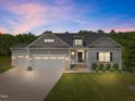 Charming home featuring a three-car garage and professionally landscaped front yard at dusk at 40 Cinnamon Teal Way, Youngsville, NC 27596