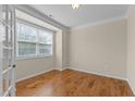 Neutral bedroom featuring hardwood floors, crown molding, window with blinds and natural light at 1021 Traditions Meadow Dr, Wake Forest, NC 27587