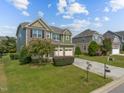 Green two story home with brick and siding exterior on a manicured lawn in residential neighborhood at 1021 Traditions Meadow Dr, Wake Forest, NC 27587