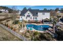 A backyard featuring a uniquely shaped swimming pool, deck, outdoor kitchen with a grill and landscaped surroundings at 105 Glasgow Dr, Clayton, NC 27520