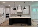 Modern kitchen featuring an island, custom cabinets, stylish light fixtures, and stainless steel appliances at 122 Sanderway Dr, Chapel Hill, NC 27516