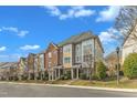 A row of brick and siding townhouses with manicured landscaping sits under a blue sky with scattered clouds at 131 Dove Cottage Ln, Cary, NC 27519