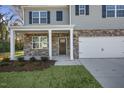 Up close view of a new two-story home featuring stone accents, a covered porch and a two-car garage at 2573 Summersby Dr, Mebane, NC 27302
