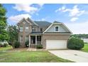 Attractive brick home boasting a two-car garage, covered porch, and complemented by lush green lawn and mature tree at 378 Oak Alley Trl, Clayton, NC 27527