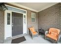 Inviting front porch with neutral brick and concrete flooring featuring comfortable wicker seating with orange cushions at 378 Oak Alley Trl, Clayton, NC 27527
