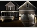 Charming two-story home with a welcoming front porch, stone accents, and a two-car garage at night at 525 Marion Hills Way, Knightdale, NC 27545