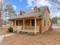 Charming exterior showcasing a cozy front porch and beautifully landscaped yard under a bright, partly cloudy sky at 582 Pollyanna Rd, Henderson, NC 27537