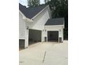 Spacious three-car garage with white siding, stone accents, and ample parking space at 60 Valebrook Ct, Youngsville, NC 27596