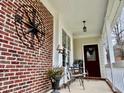 Inviting covered porch features brick accents, seating, and decorative details at 7710 Astoria Pl, Raleigh, NC 27612
