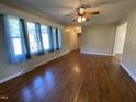 Spacious living room featuring hardwood floors, a ceiling fan, and large windows with blue curtains at 103 W Thorndale Dr, Oxford, NC 27565