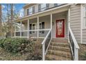 Inviting covered front porch with a red front door, white railings and brick stairs at 113 Bonner Ct, Cary, NC 27511