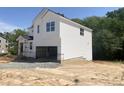Side view of a two-story home featuring a white exterior, visible foundation, and an attached unfinished two-car garage at 212 Fast Pitch Ln, Four Oaks, NC 27524