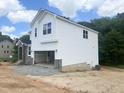 Side view of a new construction home showing white siding, stone accents and two-car garage at 212 Fast Pitch Ln, Four Oaks, NC 27524