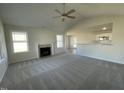 Bright living room with a cozy fireplace, plush carpet, and ample natural light from large windows at 24 Heatherglenn Cir, Princeton, NC 27569