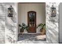 Close up of beautiful wood front door framed by black lanterns and white brick, potted plants flanking entrance at 3513 Eden Croft Dr, Raleigh, NC 27612
