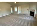Spacious living room featuring plush gray carpeting, a ceiling fan, and a cozy fireplace at 39 Flatland Dr, Princeton, NC 27569