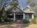Charming two-story home with a covered porch, brick pathway, manicured landscaping, and awnings on the first floor at 405 N Massey St, Selma, NC 27576