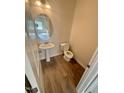 Cozy half bathroom with wood-look floors, a pedestal sink, and toilet at 72 E Victory View Ter, Smithfield, NC 27577