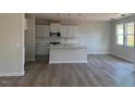 Open-concept kitchen with stainless steel appliances, a center island, white cabinets, and elegant pendant lighting at 82 Fairwinds Dr, Lillington, NC 27546