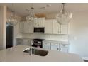 Bright kitchen with white cabinets, quartz countertops, stainless steel appliances, and modern lighting at 82 Fairwinds Dr, Lillington, NC 27546